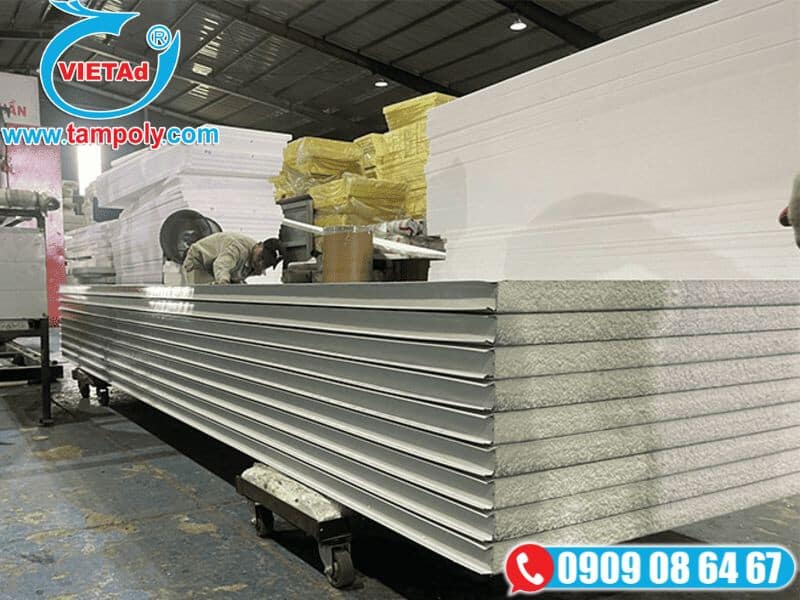 Tấm panel cách nhiệt EPS được xếp trên xe đẩy trong nhà xưởng, công nhân đang kiểm tra và xử lý
