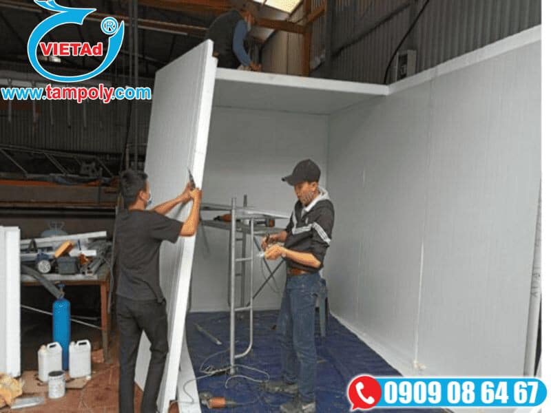 Công nhân lắp đặt tấm panel cách nhiệt để tạo phòng cách nhiệt, sử dụng dụng cụ và giàn giáo trong công trình